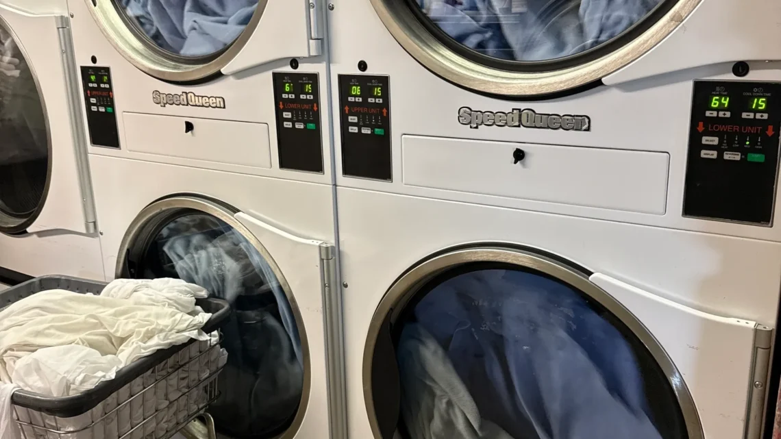 Stacked commercial dryers tumbling blue laundry